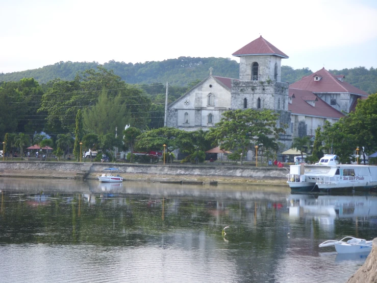 an old church is across the river from boats