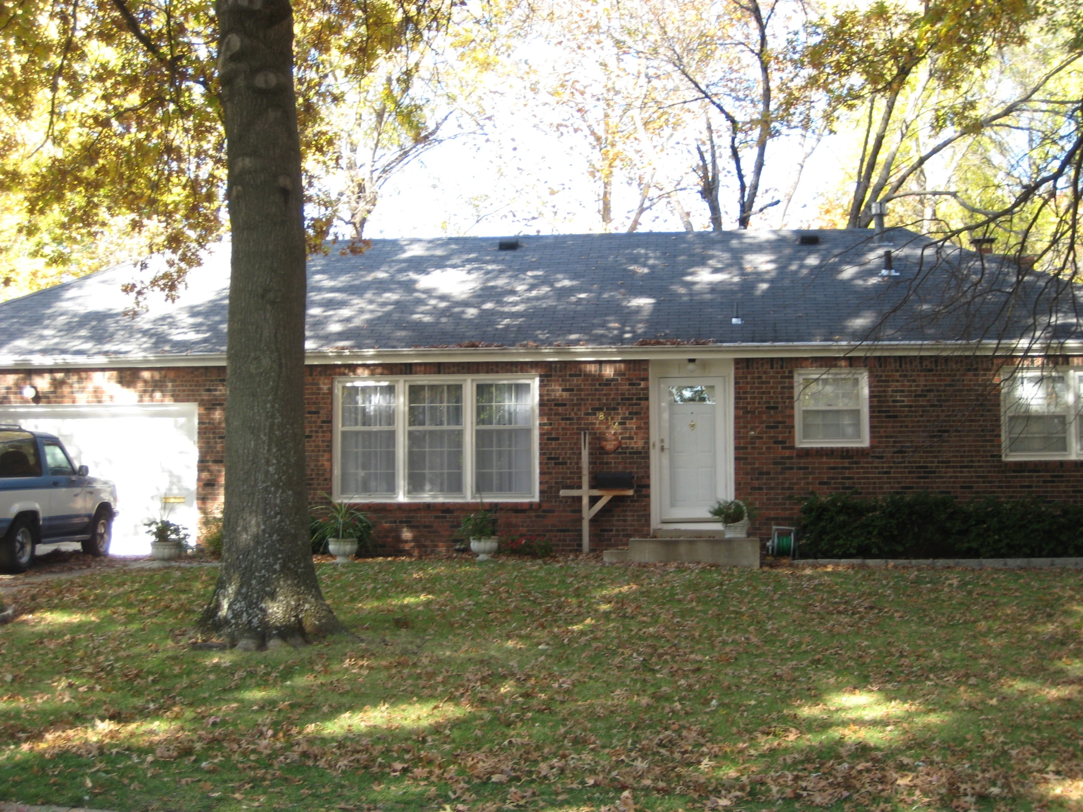 the house is made of brick with two windows on one side and a garage on the other side