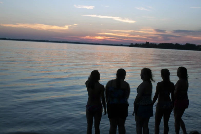 six girls standing on the beach watching the sunset