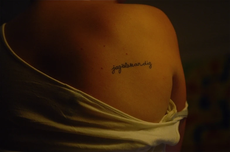 a woman has a small handwriting tattoo on her left shoulder