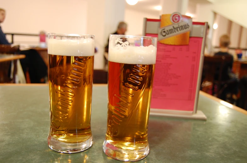 two tall glasses of beer sitting on top of a table