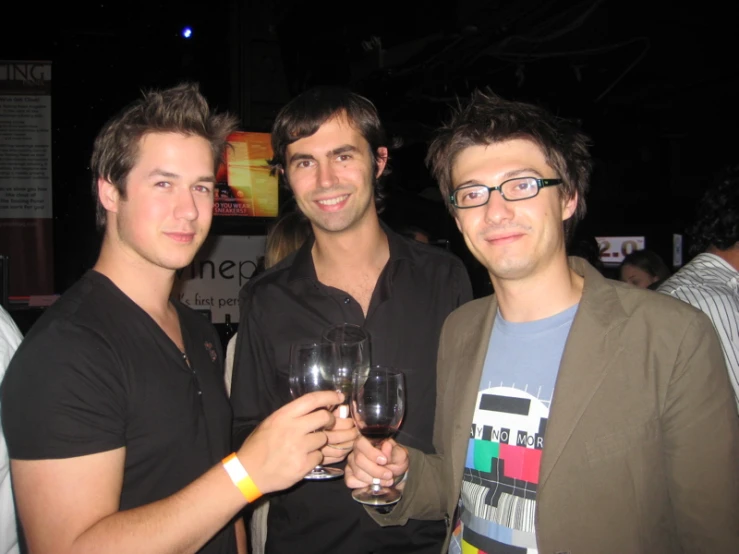 a group of young men standing next to each other holding glasses