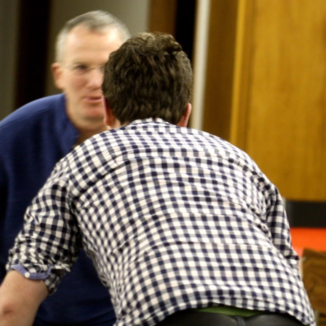 two guys with blue shirts are talking together