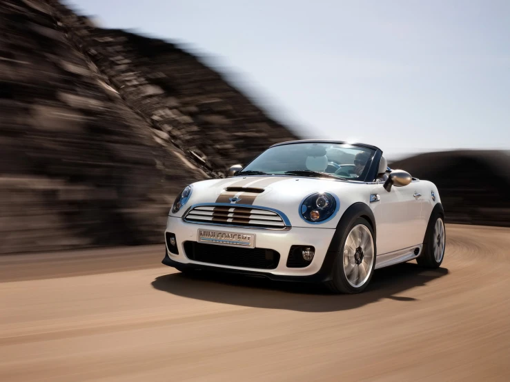 a white mini convertible driving down a road