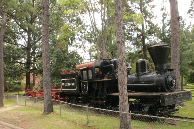 an old black train engine is sitting in the woods