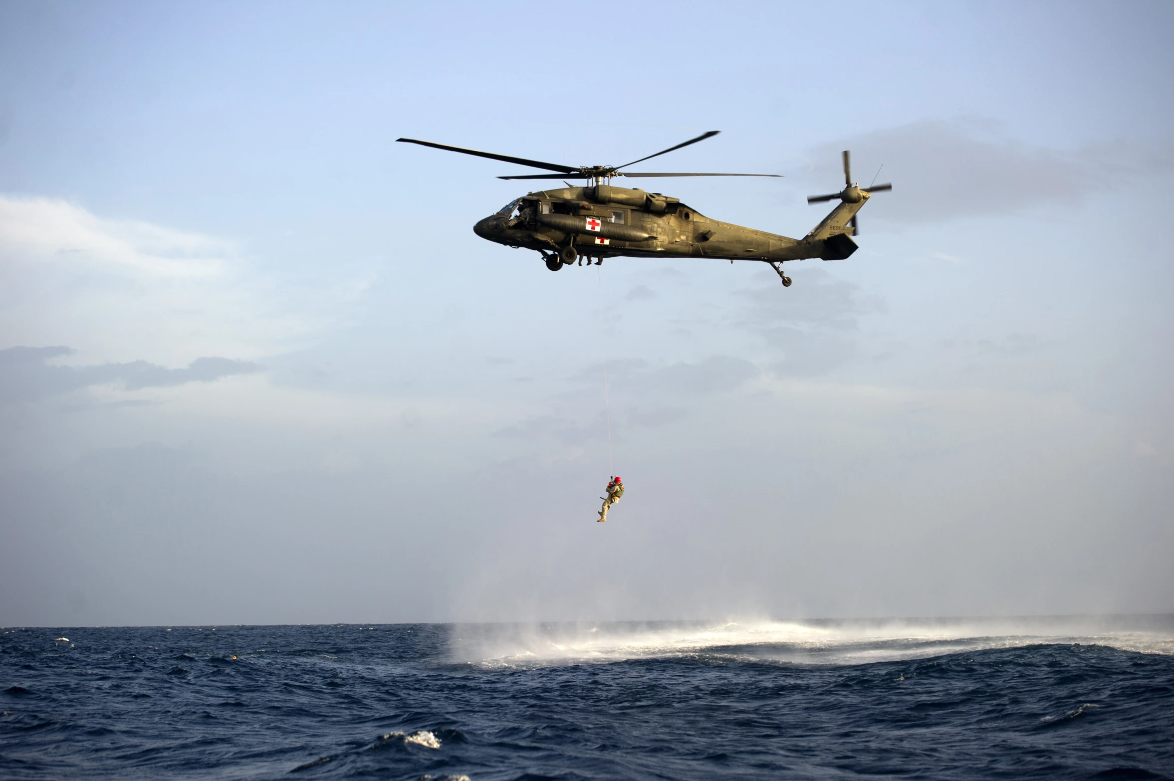 a helicopter is dropping a parachute over the water