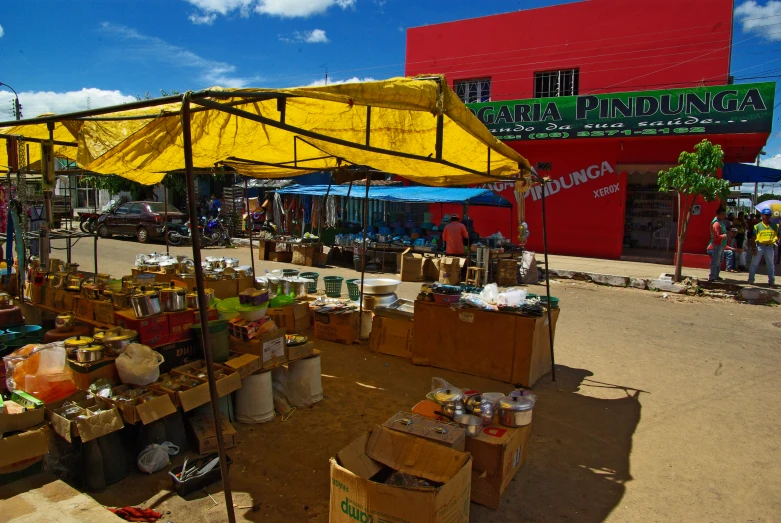 a large open market with boxes, containers and umbrellas