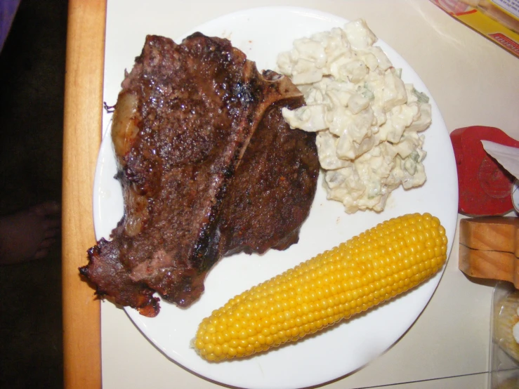 plate of food with meat, corn on the cob and mashed potatoes