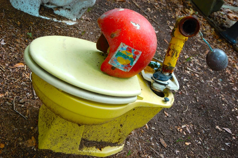 a toilet bowl with a broken lid sits on a garbage can