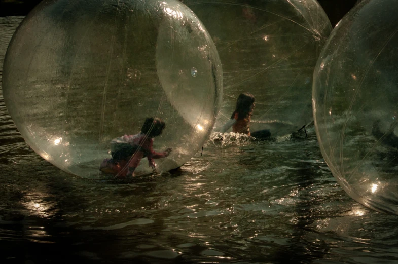 a man in water holding onto two large inflated ball floats