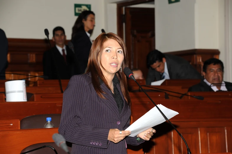 a woman in black jacket holding papers in front of the camera