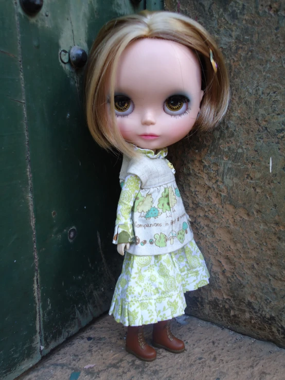 a doll is standing beside a rock wall