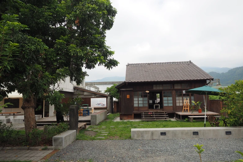 a wooden hut in the middle of the grass with people walking around it