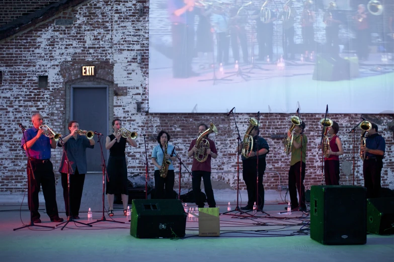 a band playing outside on stage next to people