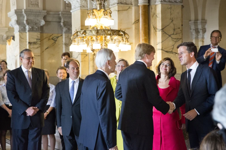 many people standing in a group, some dressed in suits