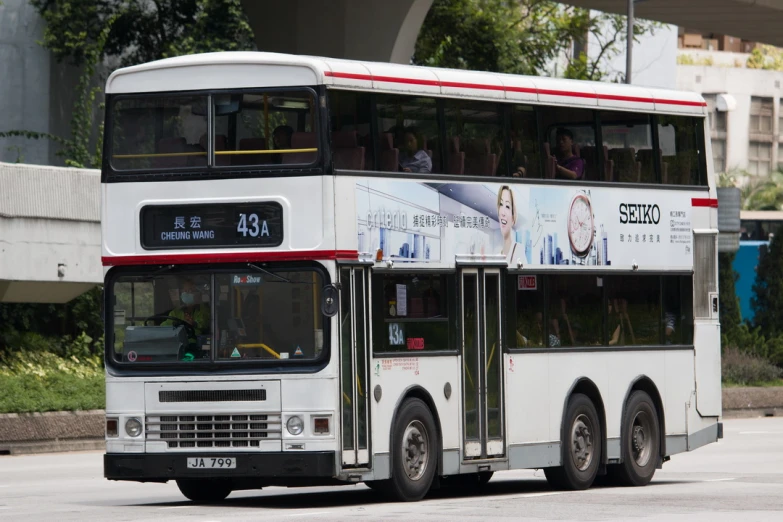 the double decker bus drives down the road near a bus stop