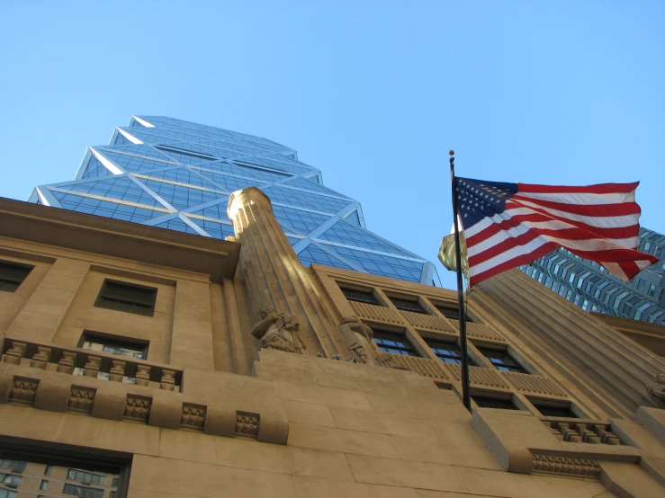 an american flag flies next to a skyscr