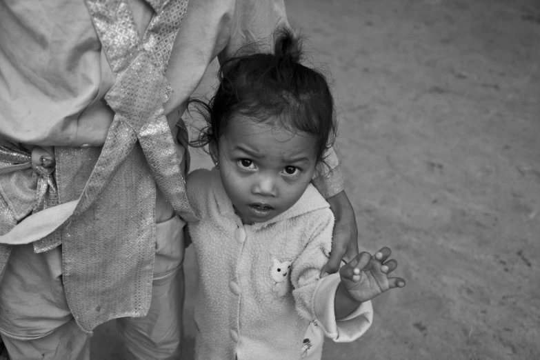 a young child holds on to his mother's arm