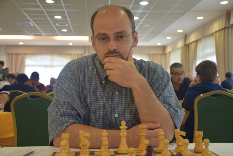 a man leaning on his chin with chess in hand