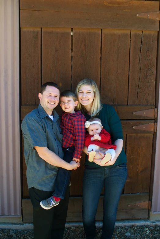 an adult couple with two children in front of an outside door