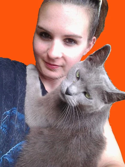 a woman in glasses holding a cat next to an orange background
