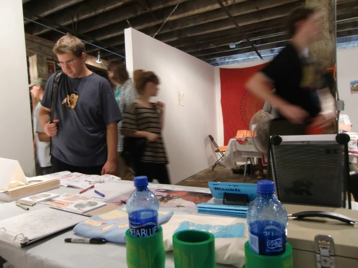 a group of people look at several paintings on a table