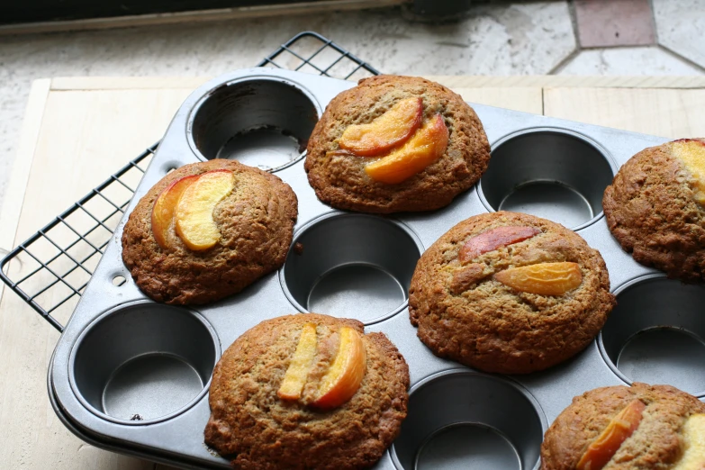 several muffins sitting in an aluminum pan with fresh fruit