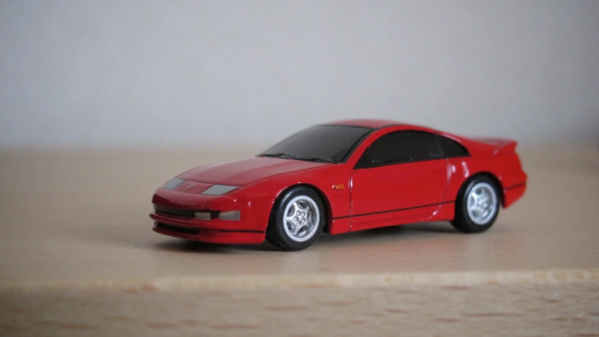 a small red toy car on top of a wooden table