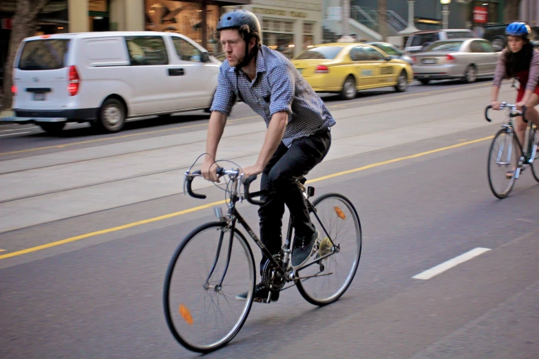 two bicyclists ride down the street in traffic