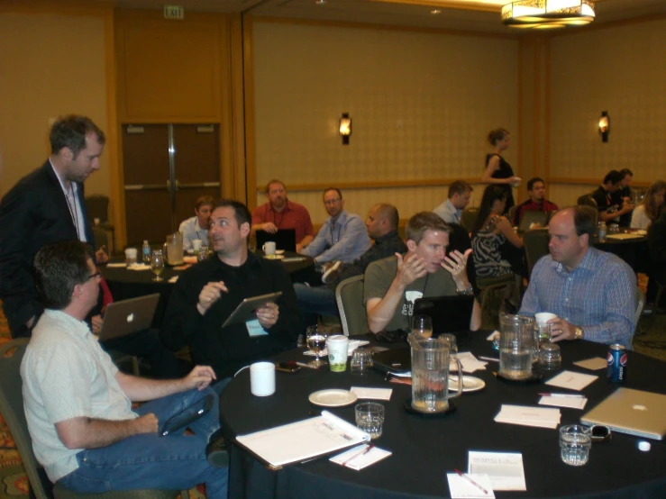 a group of men sitting at tables using laptops