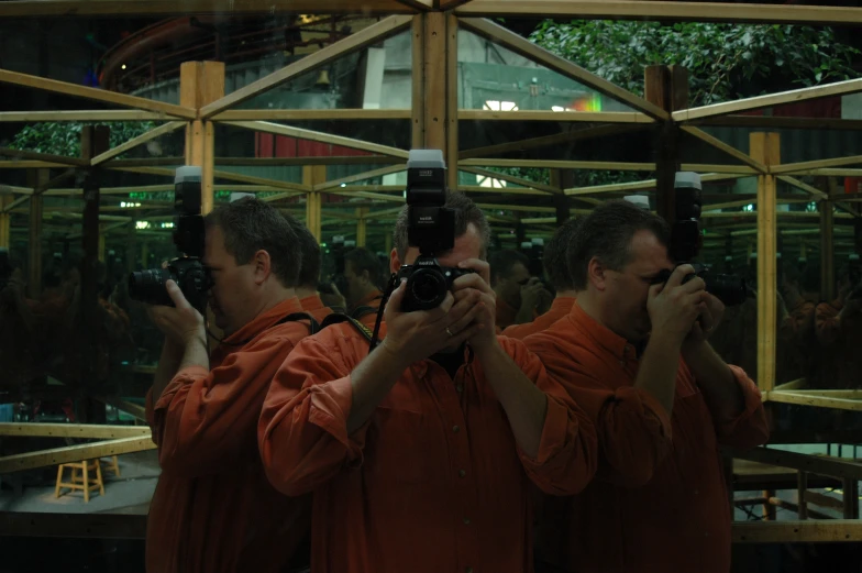 two men wearing orange robes take pictures with their cameras