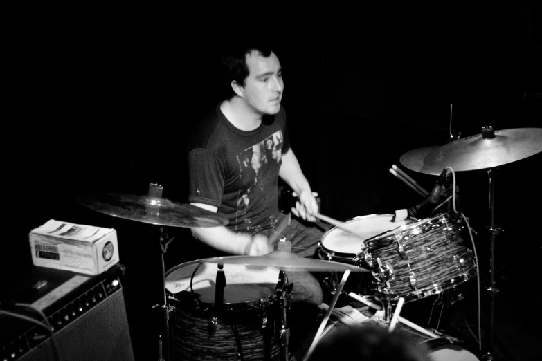 the man sits behind a set of drums and a tube