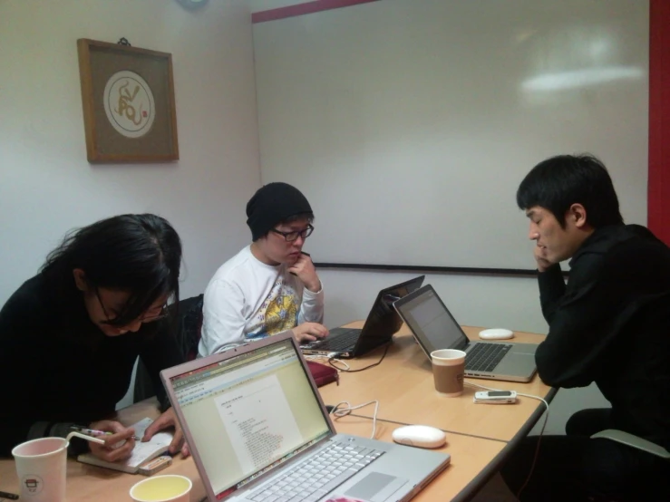 three people using laptop computers at a table