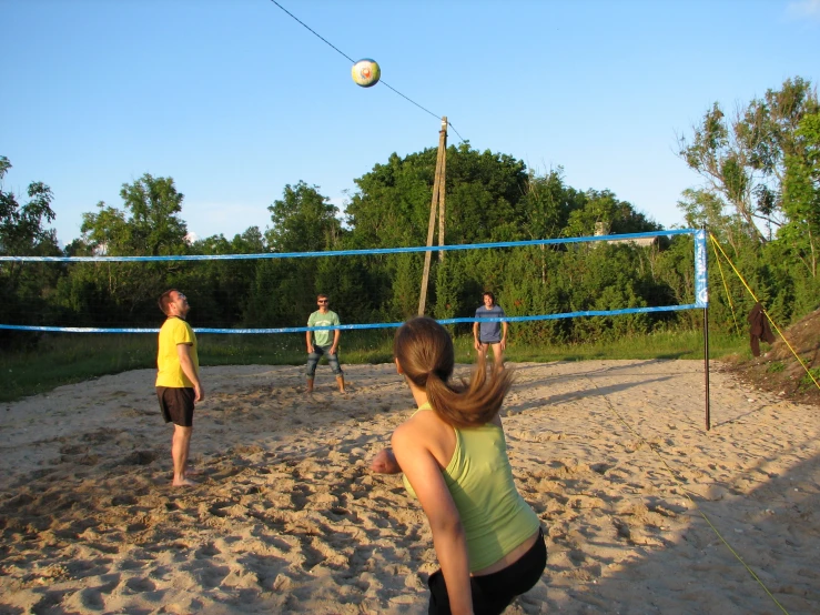 several young people playing volley ball in the sand