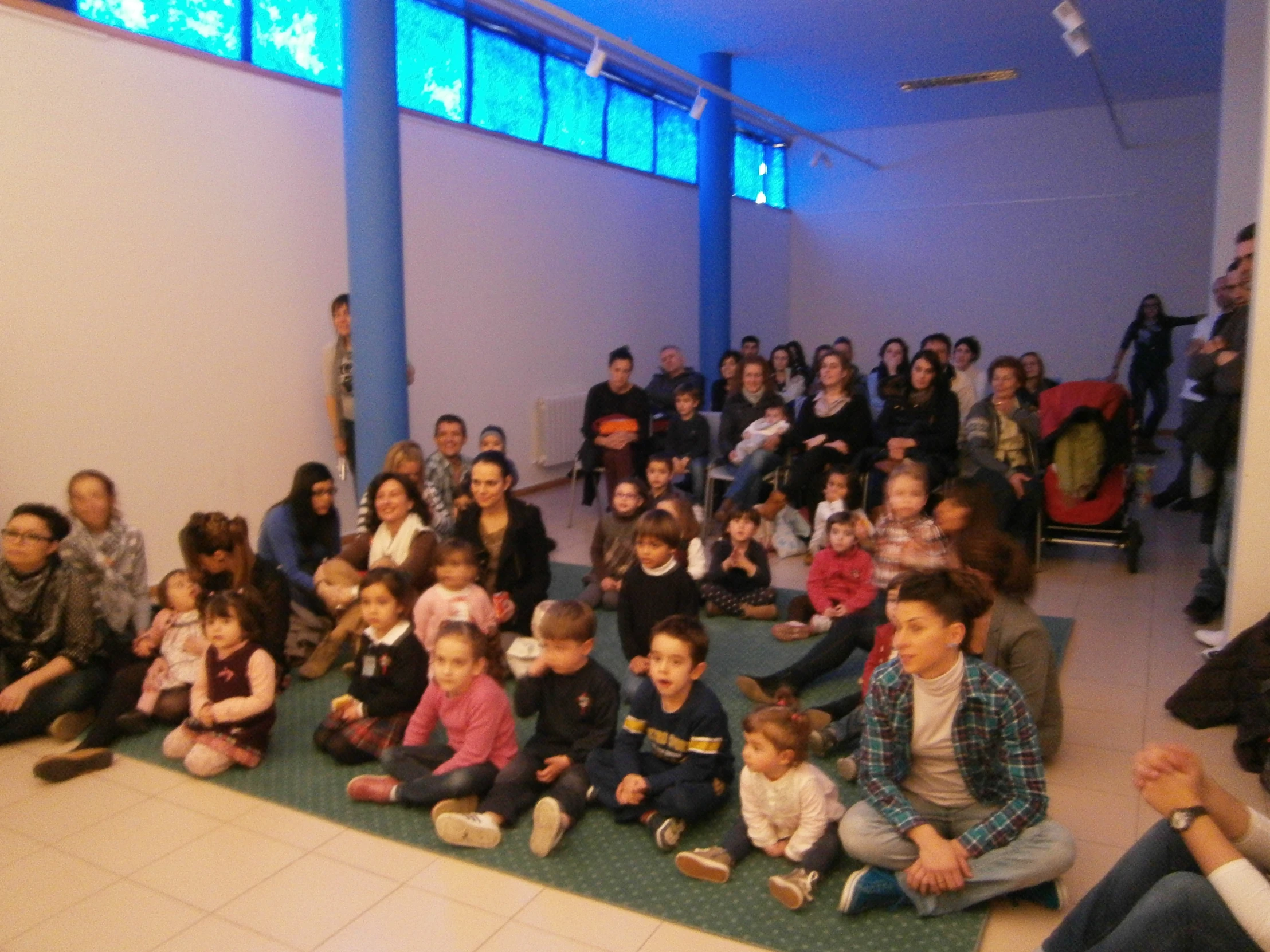 group of s sitting on the floor with adults and children in background