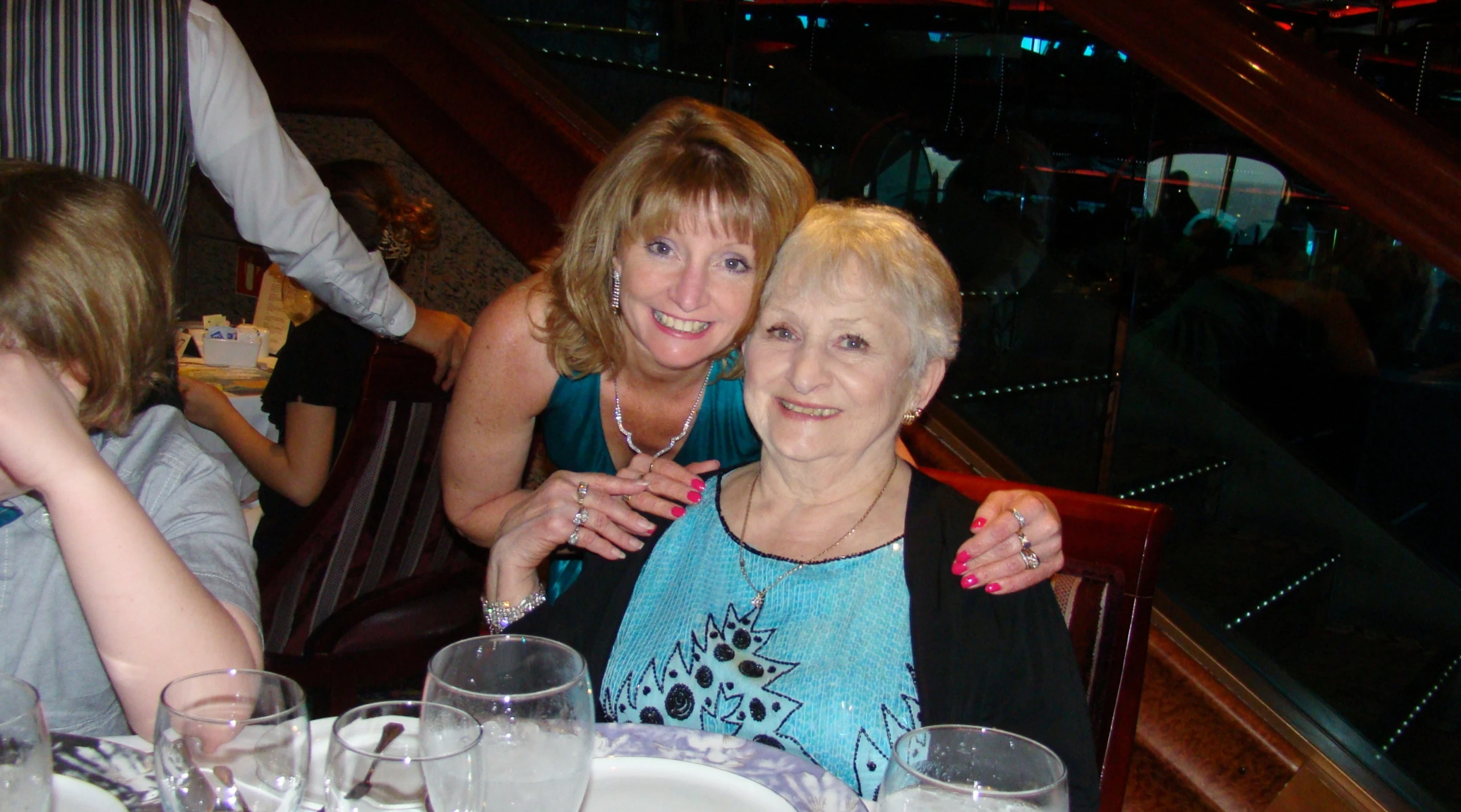 two women at a dining table, one sitting at the table