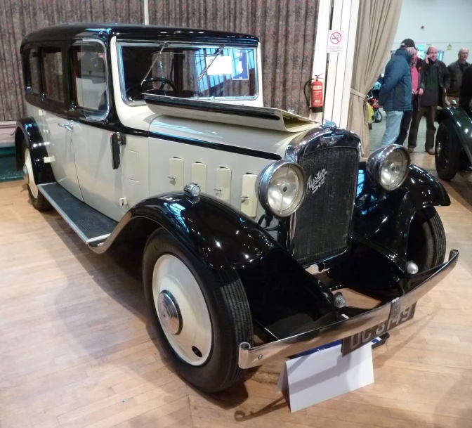 an old car parked on a wooden floor inside a building