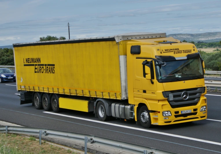 a yellow semi truck is driving on the highway