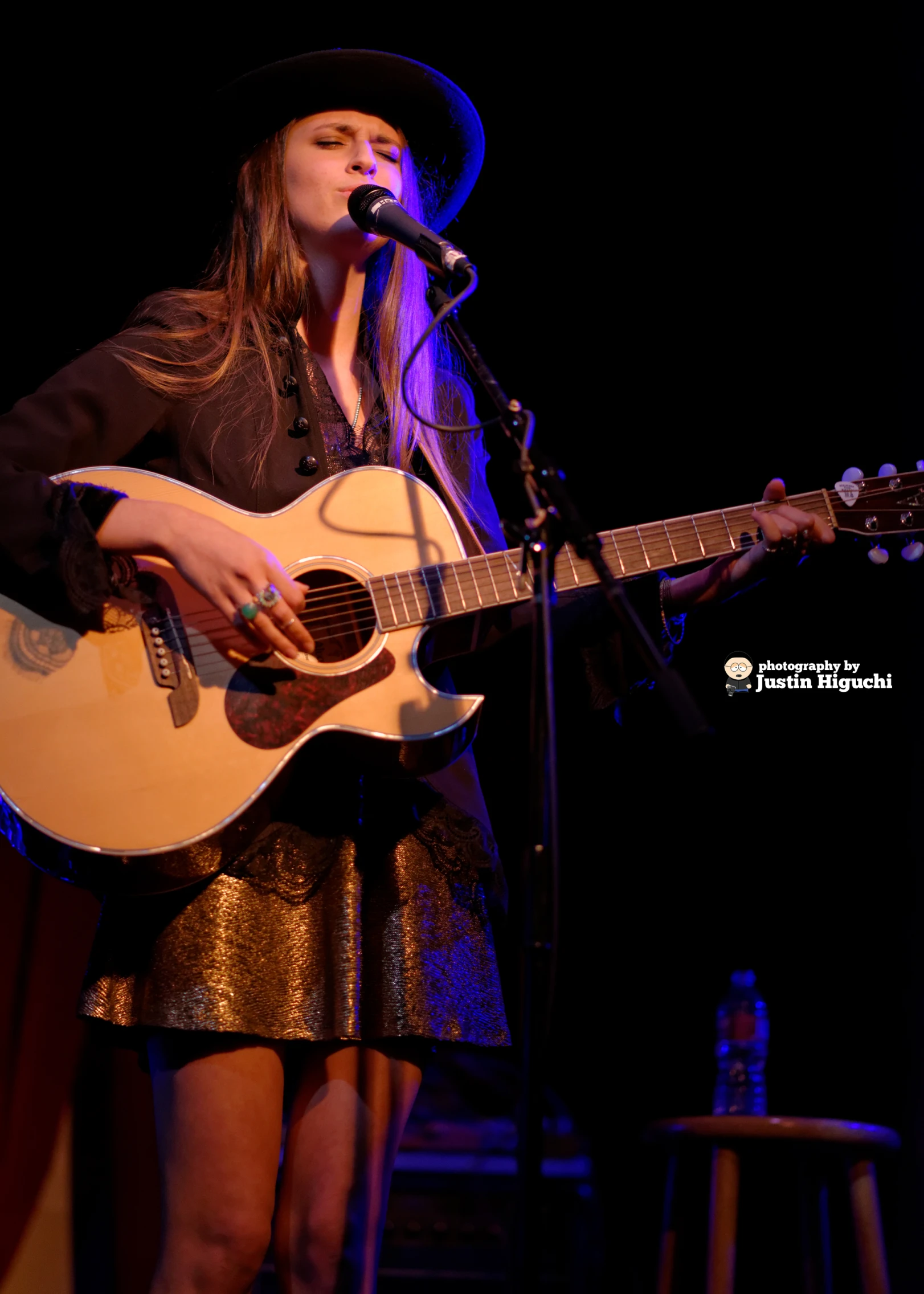 a woman with a cowboy hat playing guitar