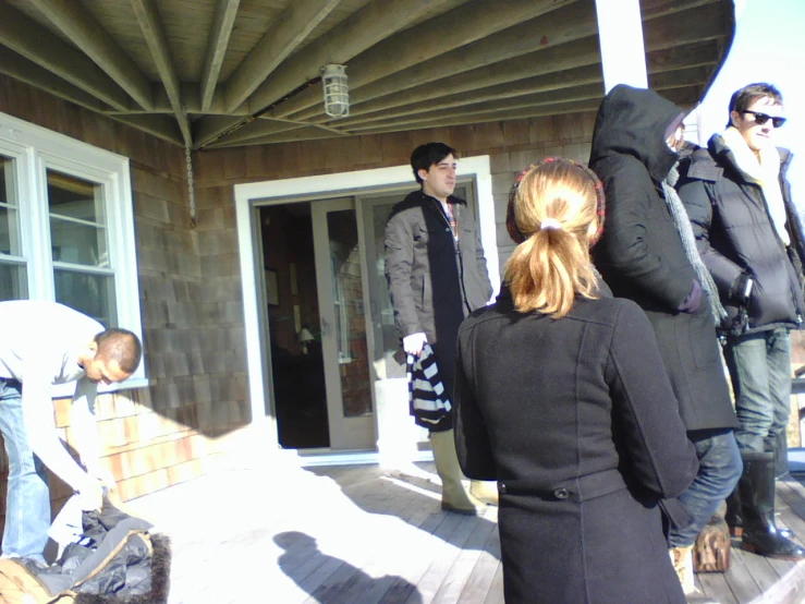 people gathered on porch with their luggage and a man reaching out his door to open the door