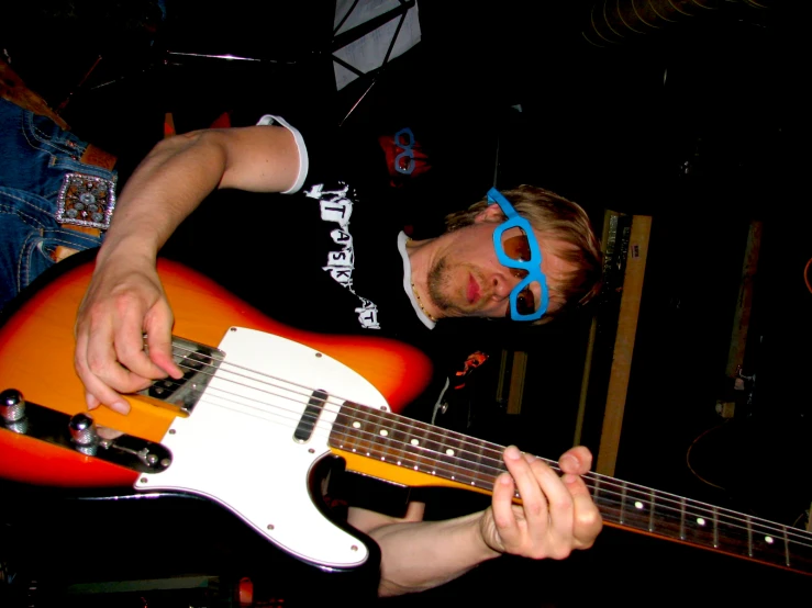 a man wearing blue goggles holding up a guitar