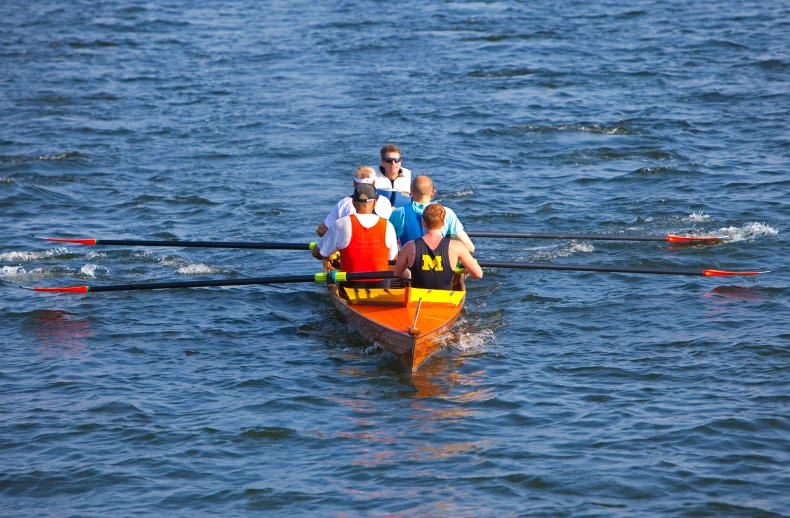 four people in a canoe with poles and oars