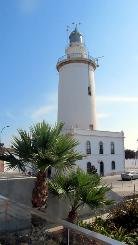 a white and gray light house next to trees