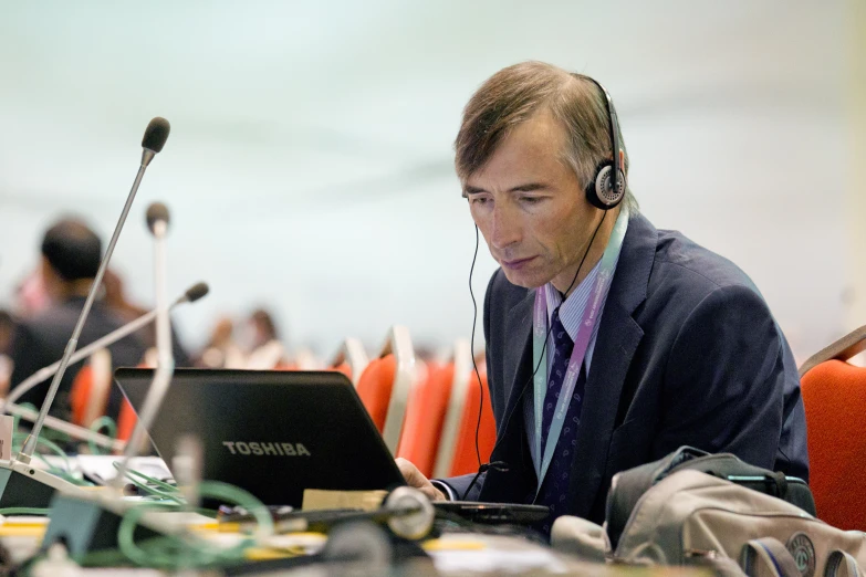 man sitting at a desk while working on his laptop computer