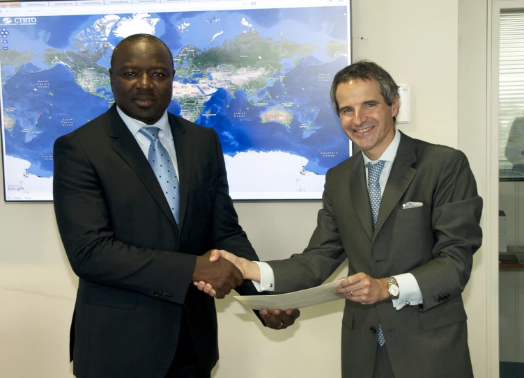 two men shake hands while wearing suits and ties