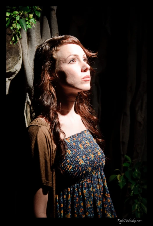 a woman standing against a tree in the dark