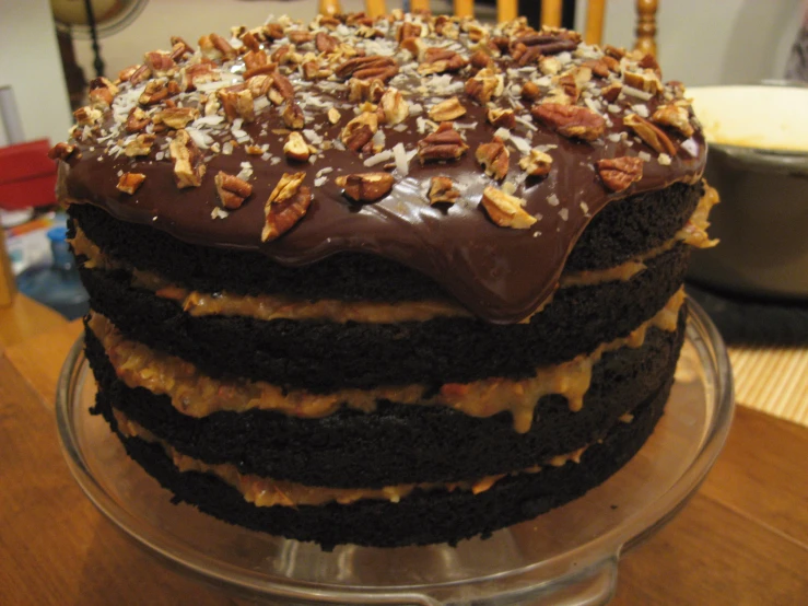 a large chocolate cake covered in nuts on a glass plate