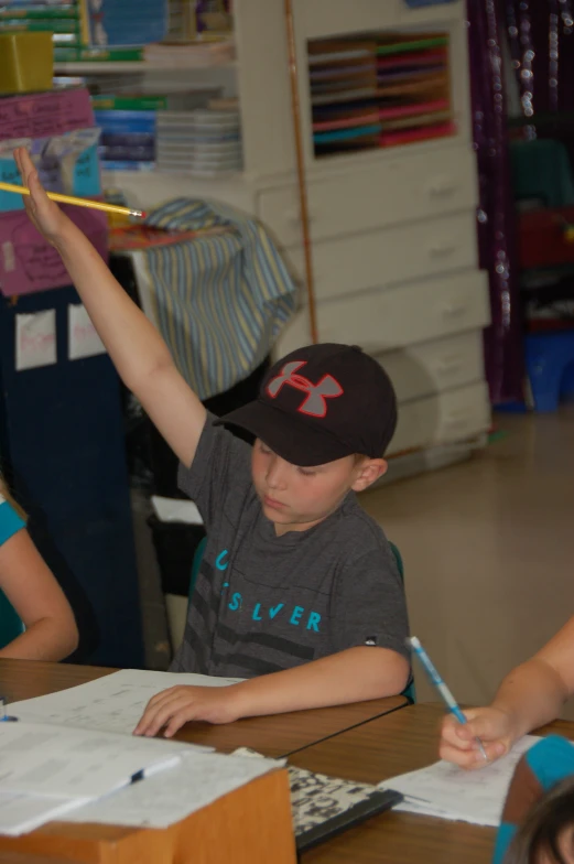 a little boy sitting at a table with a stick above his head