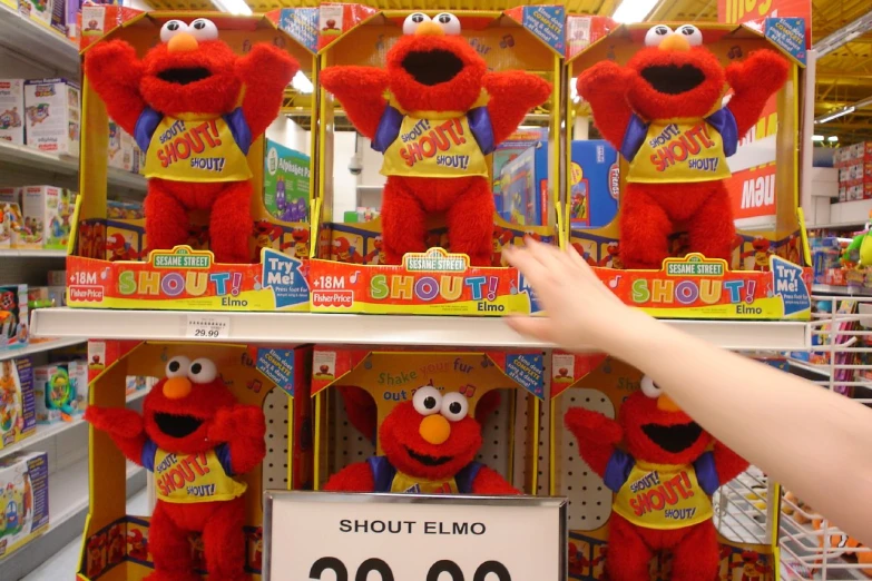 red stuffed animal with t shirt on standing behind two shelves of the store