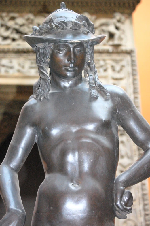 a statue of a  woman with a hat standing in front of a doorway